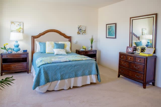 A cozy bedroom with a neatly made bed, a nightstand, and a dresser.