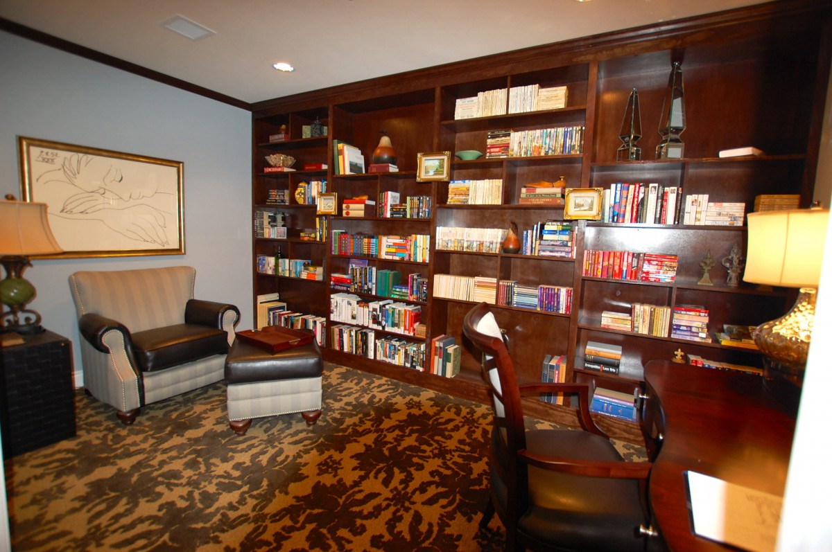 A cozy library with bookshelves, an armchair, and a desk.
