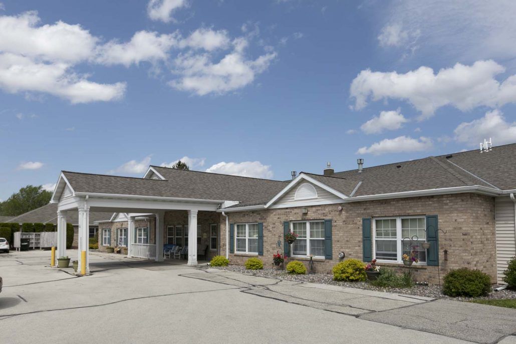 A single-story residential building with a driveway under a partly cloudy sky.