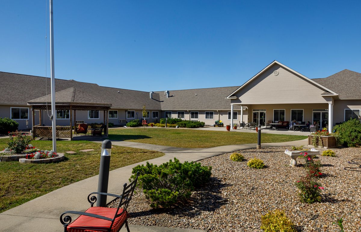 A well-maintained residential building with a landscaped courtyard and pathways on a sunny day.