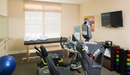 A rehabilitation room equipped with exercise machines and a treatment table.