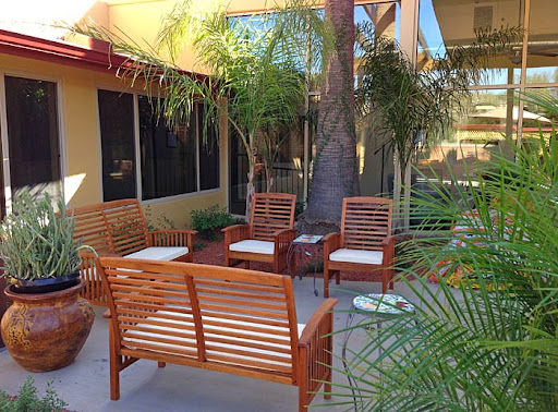 A cozy outdoor seating area featuring wooden chairs and palm trees, perfect for relaxation.