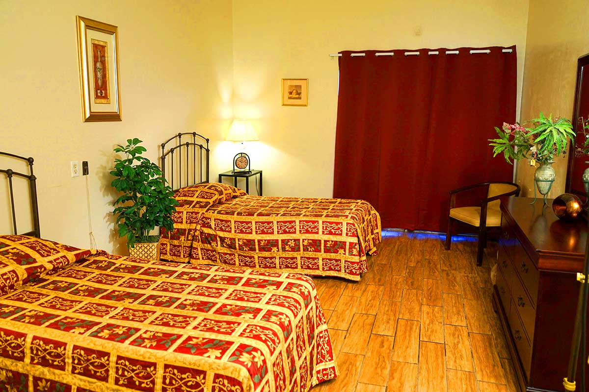 A cozy hotel room with twin beds and warm lighting.