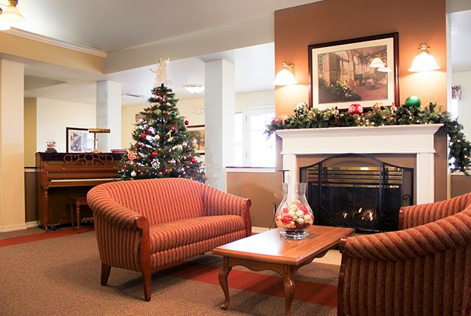 A cozy living room decorated for the holidays, featuring a warm fireplace and a beautifully adorned Christmas tree.