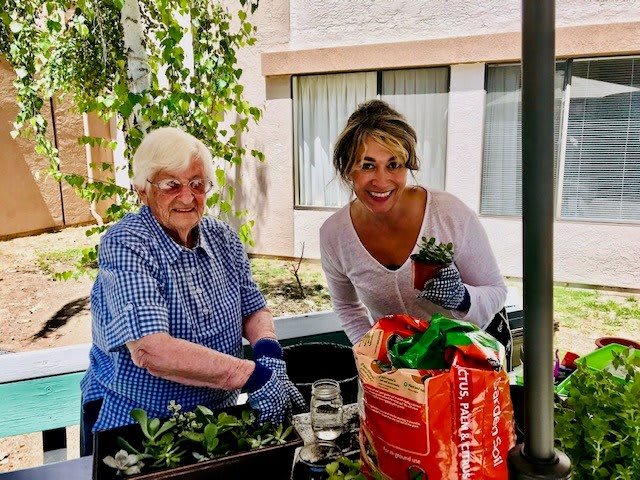 Two women enjoying gardening together outdoors.