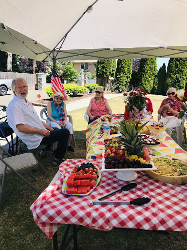 A joyful outdoor gathering with friends, enjoying a spread of delicious fruits and food under a sunny sky.
