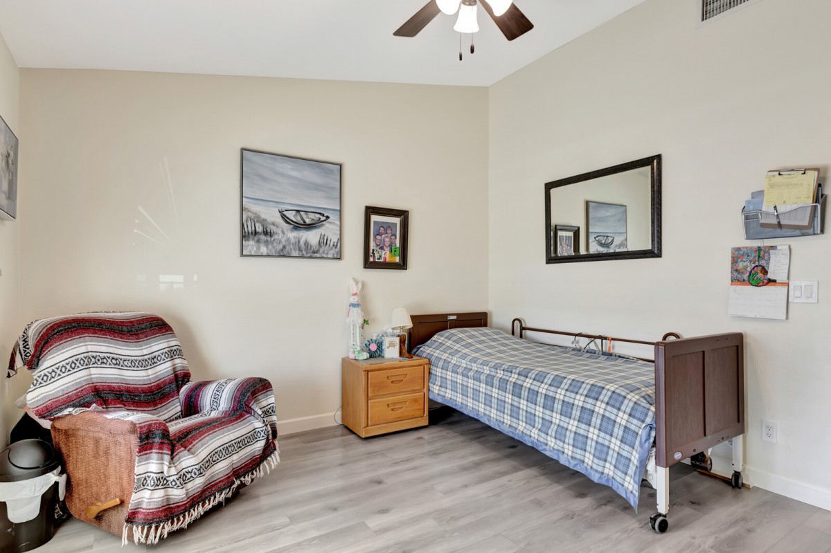 A cozy bedroom featuring a single bed, armchair, and wall art.