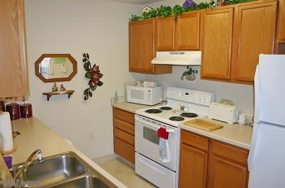 A small kitchen with wooden cabinets, a stove, and a microwave.