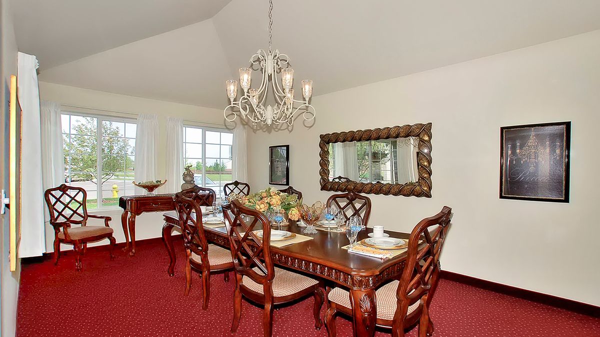 An elegant dining room with a chandelier and wooden furniture.