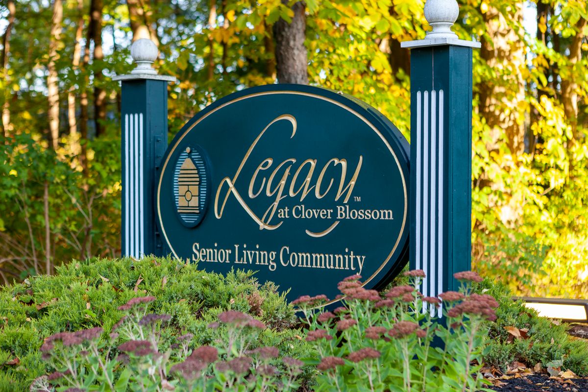 Sign for Legacy at Clover Blossom Senior Living Community surrounded by nature.