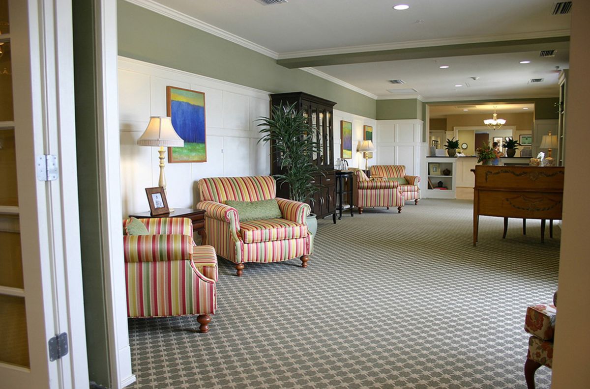 A cozy living room featuring striped armchairs, decorative lamps, and artwork on the walls.