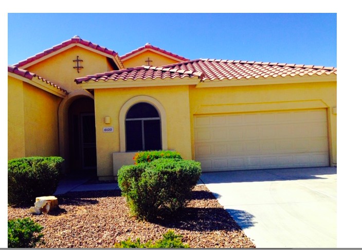 A suburban yellow house with a double garage and well-maintained landscaping.