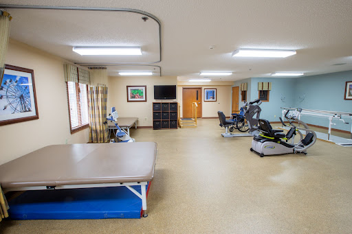 A spacious physical therapy room equipped with exercise machines and a treatment table.