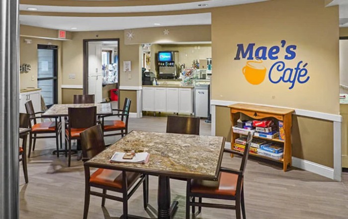 Interior view of a cafe with seating area, displaying tables, chairs, and a counter with coffee machines.