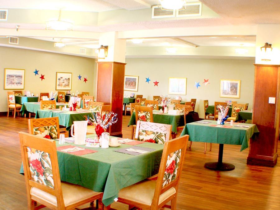 A brightly lit dining area with neatly arranged tables and chairs, decorated for a festive occasion.