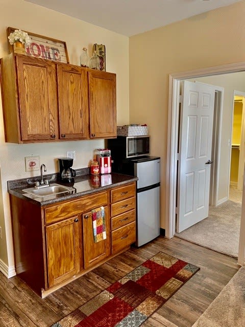 A cozy kitchenette with wood cabinets, a mini fridge, microwave, and coffee maker.