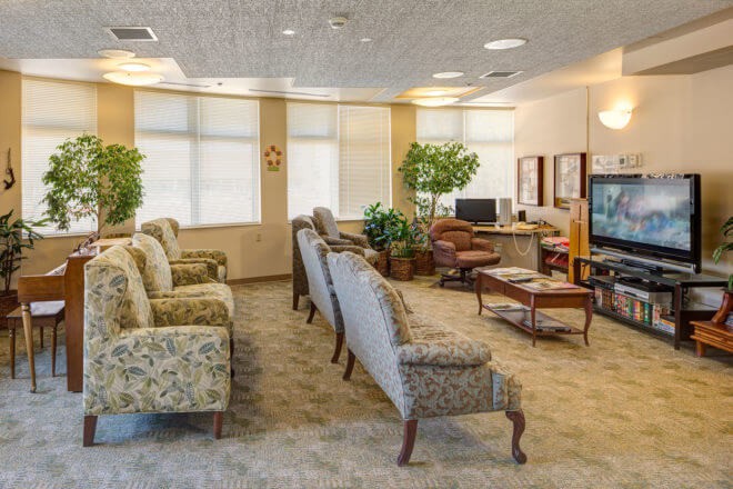 A cozy waiting room with comfortable seating, a television, and natural lighting.