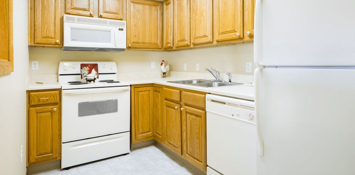 A kitchen featuring wooden cabinets, a stove, microwave, and dishwasher.