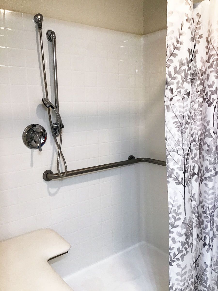 Accessible shower with grab bars and a patterned curtain.