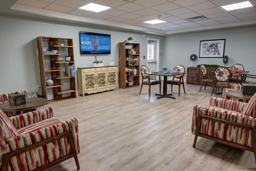 A cozy living room interior with a TV, bookshelves, and comfortable seating.