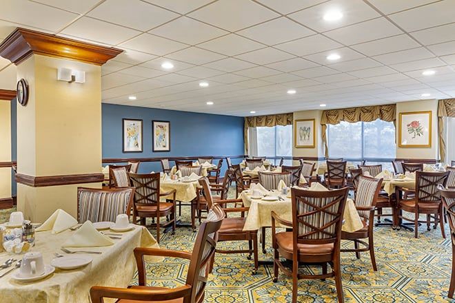 A spacious and well-lit dining room with neatly arranged tables and chairs, featuring elegant decor.