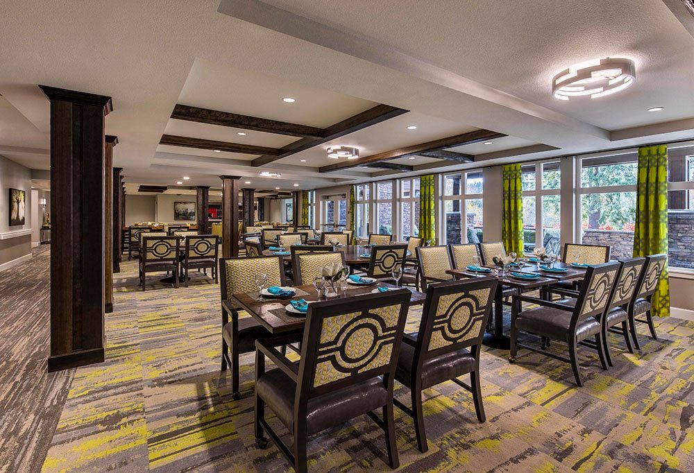 A modern restaurant interior featuring neatly arranged tables and chairs with stylish lighting and large windows.