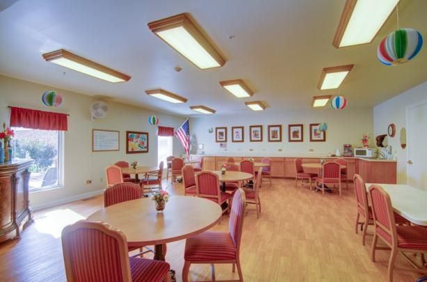 A well-lit dining area with multiple tables and chairs, featuring wall decorations and a flag.
