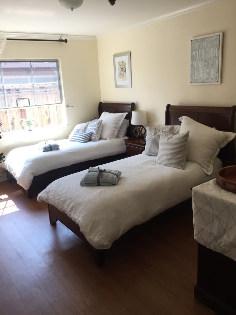 A cozy bedroom with two neatly made twin beds and ample natural light.