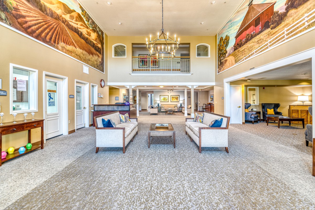 A spacious and modern lobby featuring comfortable seating, a chandelier, and large murals on the walls.