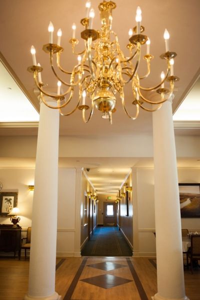 A luxurious hallway adorned with a grand chandelier and elegant columns.