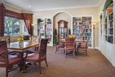 A cozy library room with bookshelves, tables, and a grandfather clock.