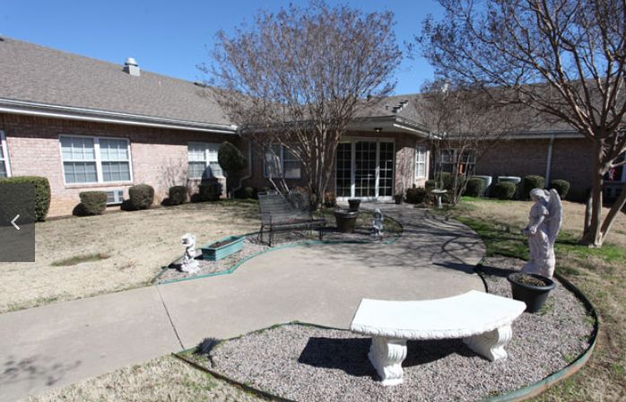 A backyard patio area with seating, a bench, and garden features.