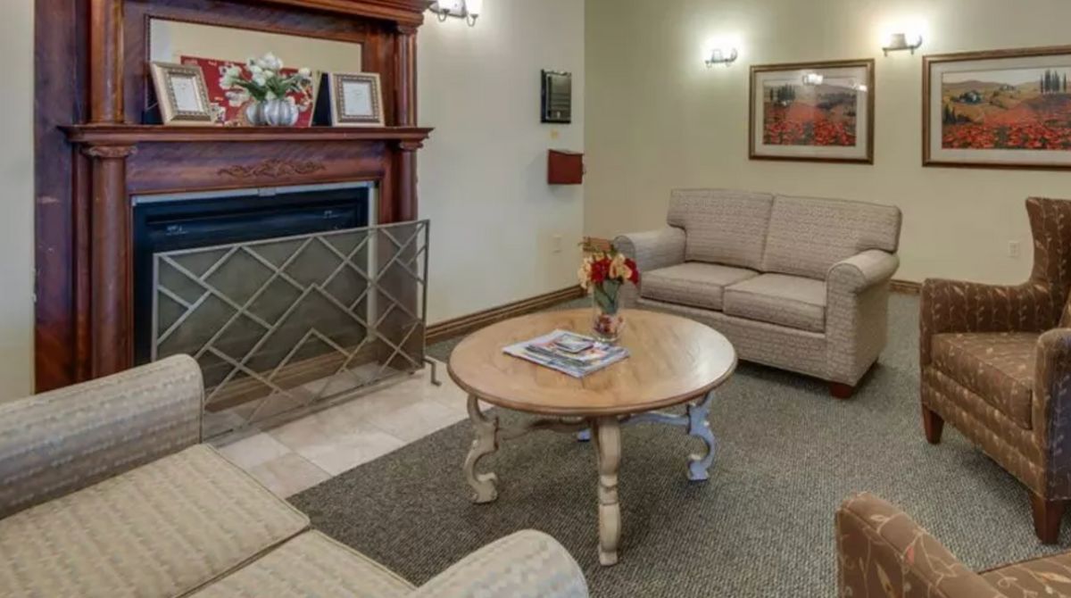 A cozy living room featuring a sofa, a wooden coffee table, and a fireplace adorned with decorative items.
