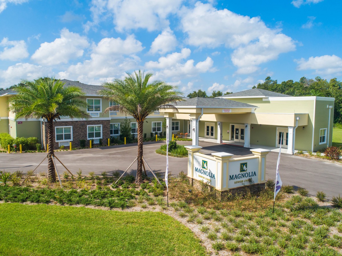 A modern building with palm trees and clear skies.