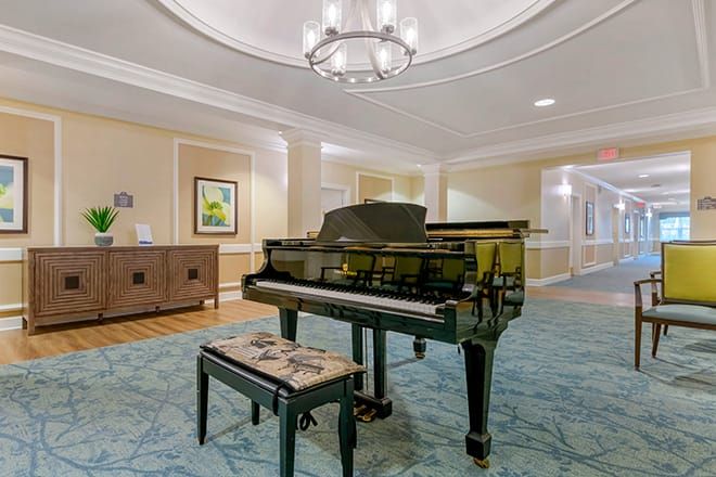 A grand piano in an elegantly decorated lobby with a chandelier and carpet.