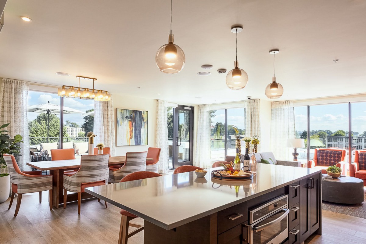 Modern kitchen and dining area with pendant lighting and large windows.