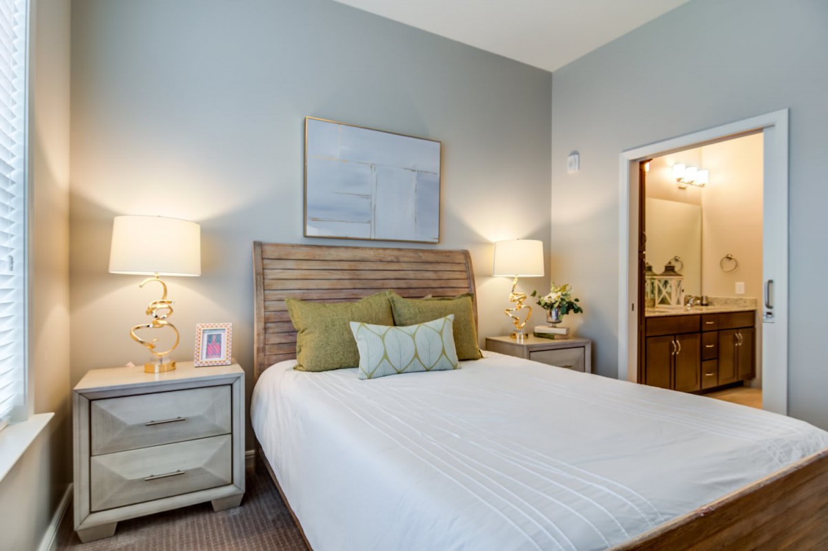 A cozy bedroom with a neatly made bed, two nightstands, and warm lighting.