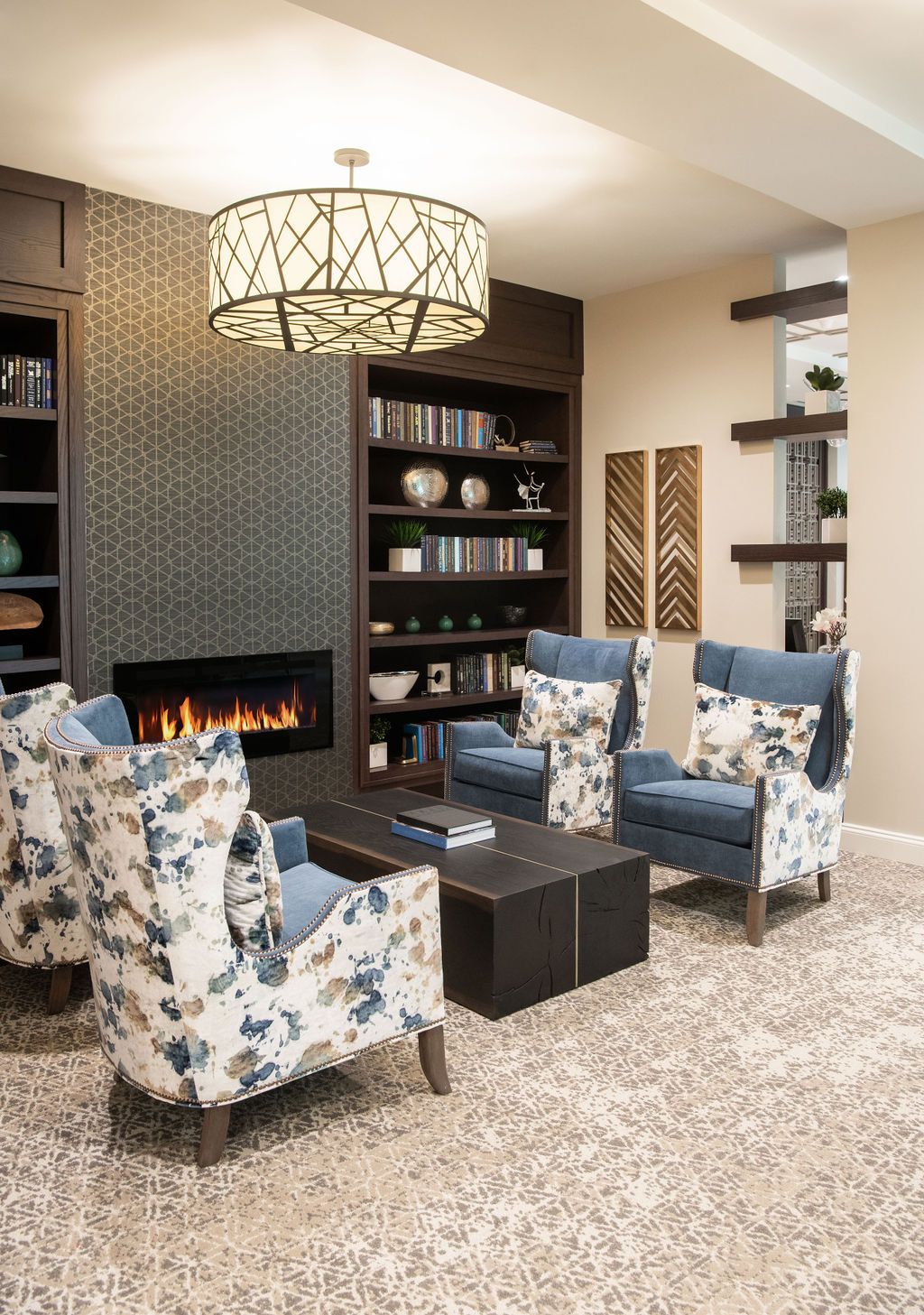 A cozy living room with floral armchairs and a modern fireplace.