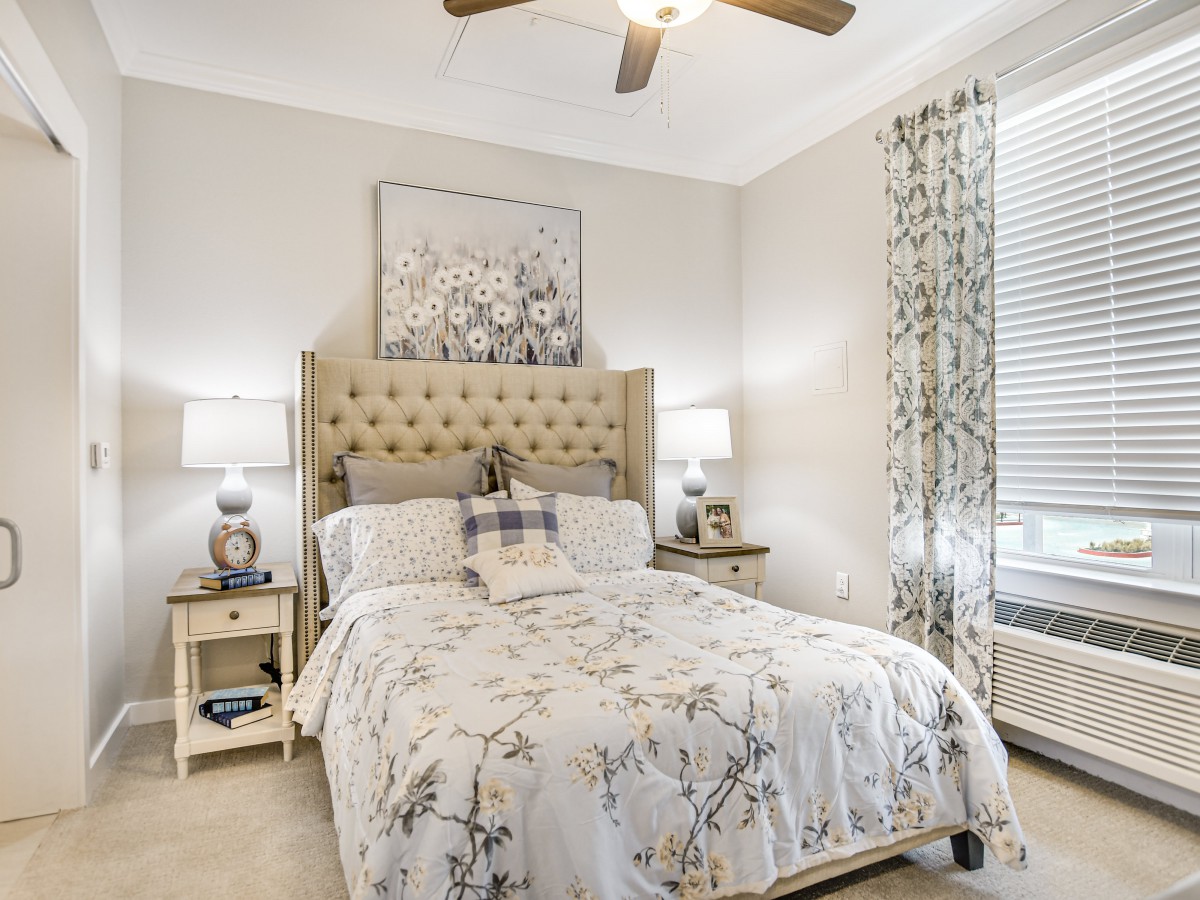 A cozy bedroom with a tufted headboard, patterned bedding, and matching decor.