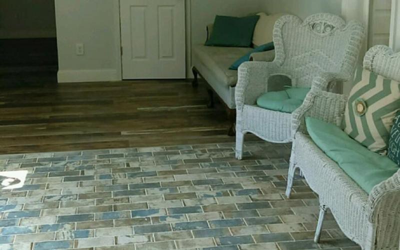 A cozy living room with wicker furniture, a patterned rug, and wooden flooring.