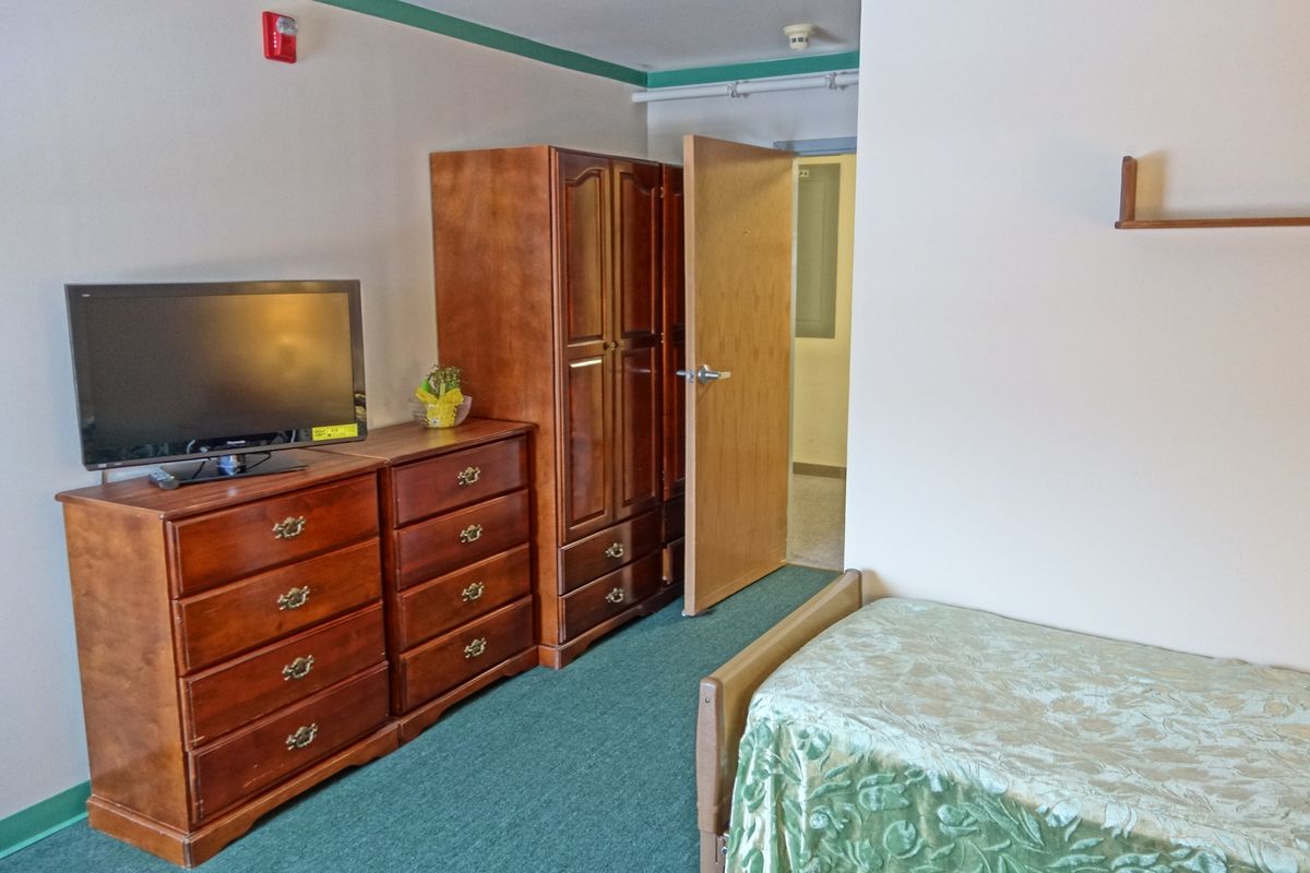 A cozy bedroom with wooden furniture, including a wardrobe, dresser, and a television.