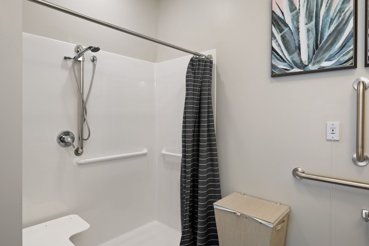 A modern bathroom with a shower, striped curtain, and wall art.