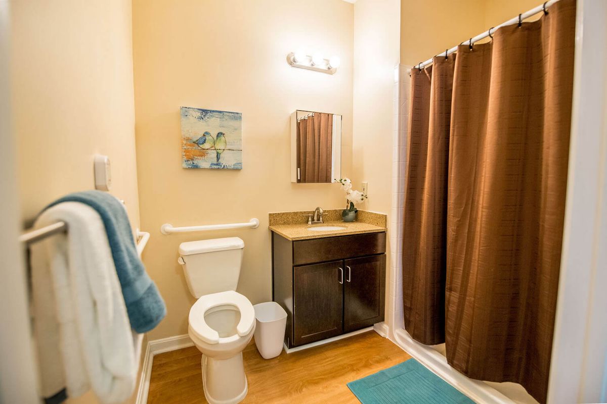 A cozy bathroom with a brown color scheme, featuring a sink, toilet, and shower curtain.