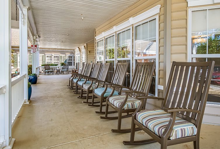 A row of rocking chairs on a porch gives a cozy and relaxing outdoor seating area.