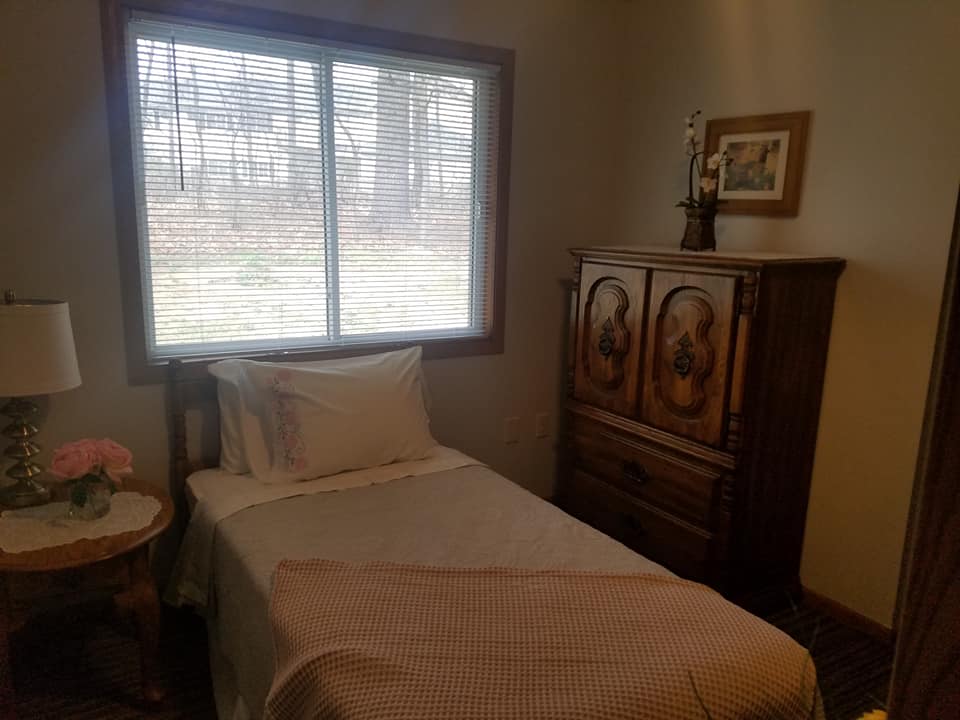 A cozy bedroom with a single bed and wooden furniture by the window.