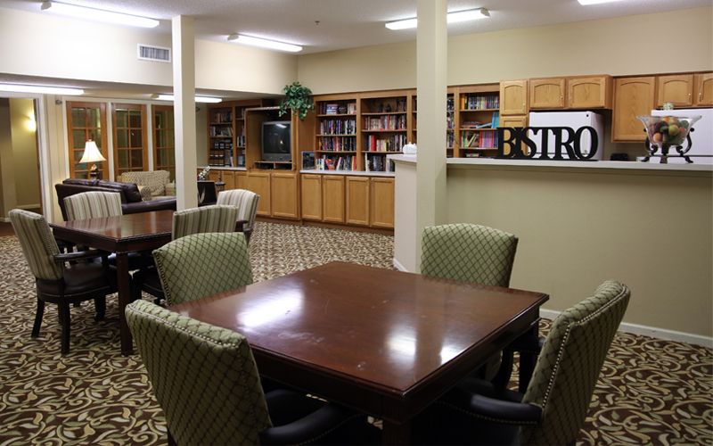 A cozy library with a wooden table, comfortable chairs, and bookshelves filled with books.