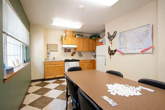A kitchen area with a table and chairs, featuring dominoes on the table.