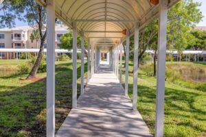A covered walkway providing a shaded path through a sunny outdoor area.