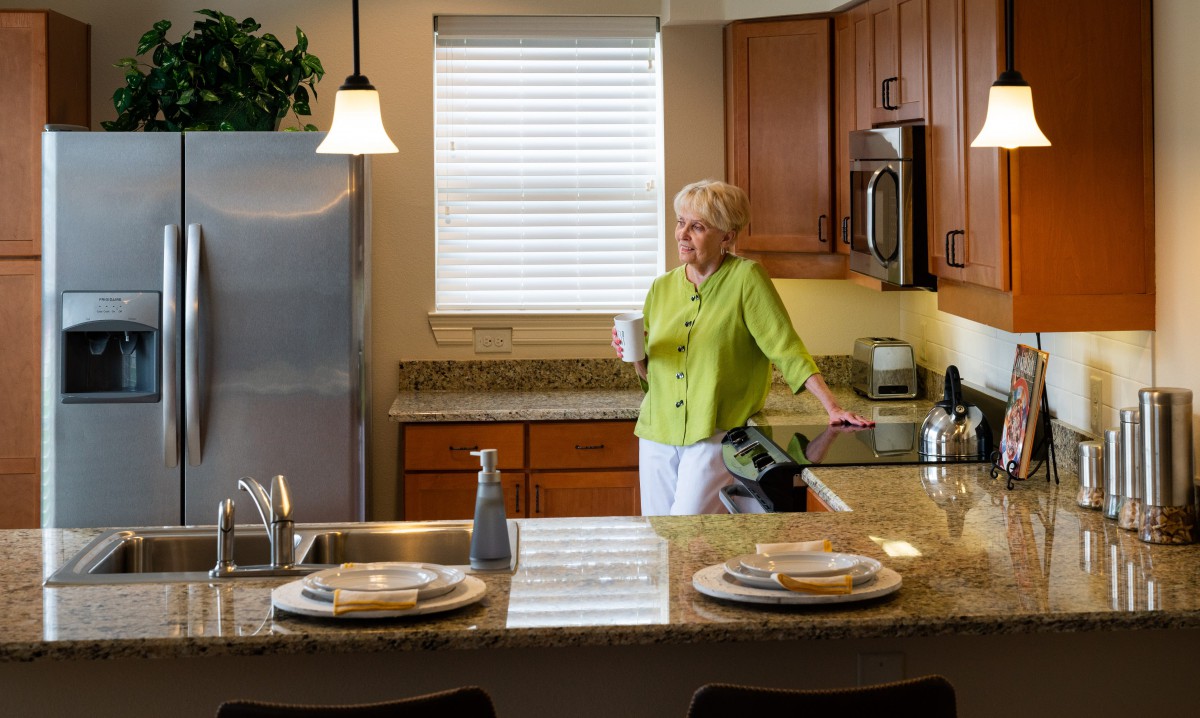 A woman enjoying a drink in a modern kitchen.