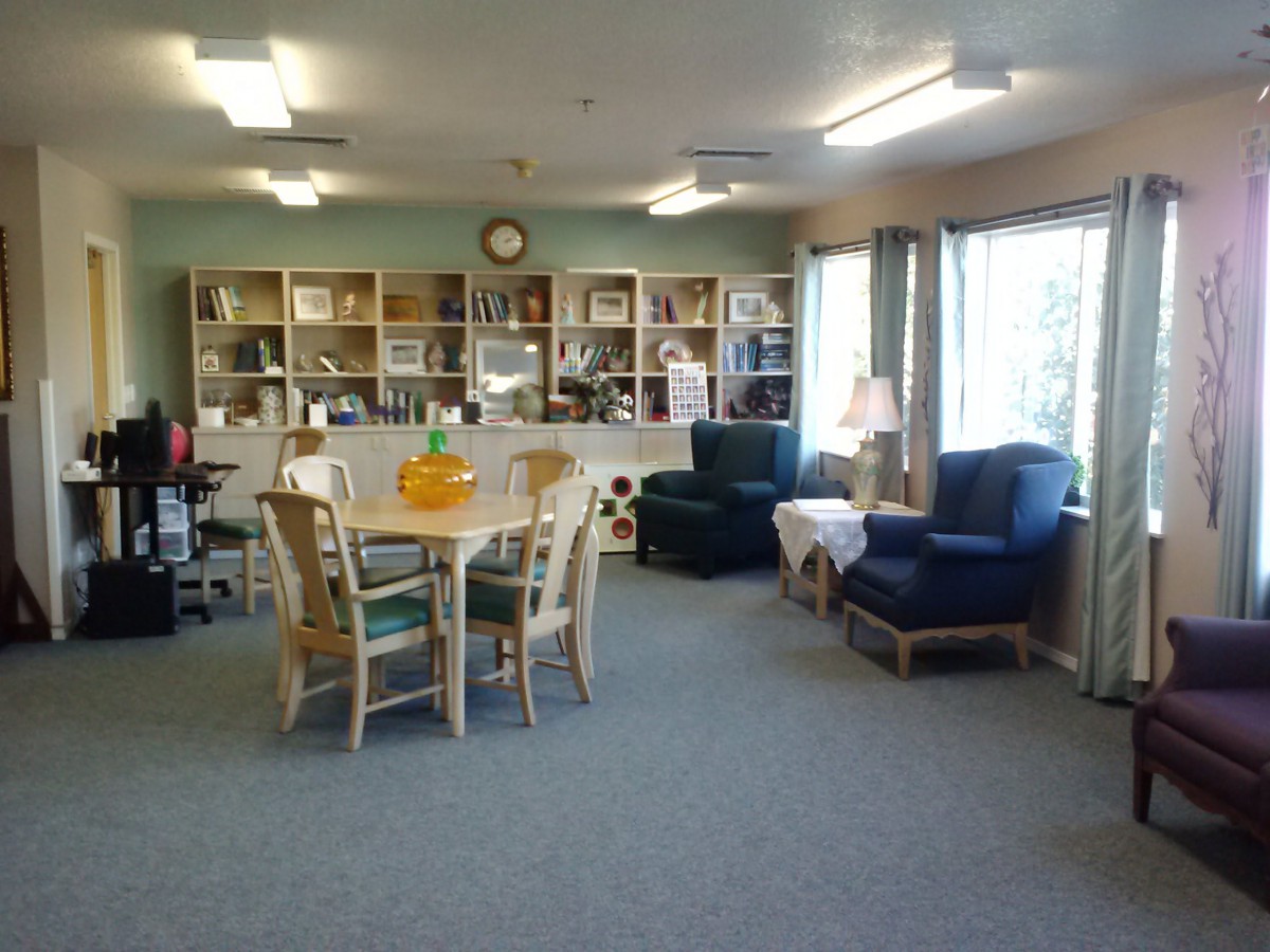 A cozy living room with a table and chairs, surrounded by bookshelves and armchairs.